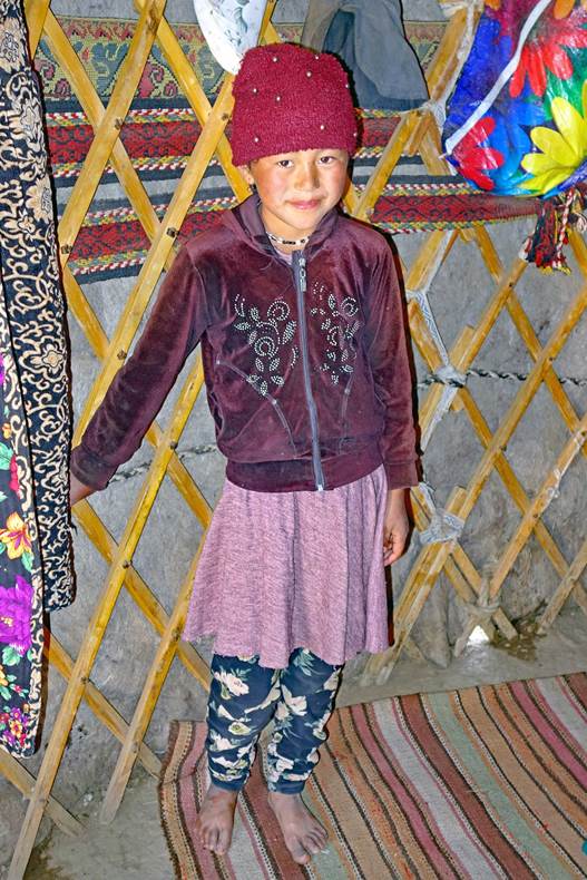 A child standing in front of a yurt

Description automatically generated