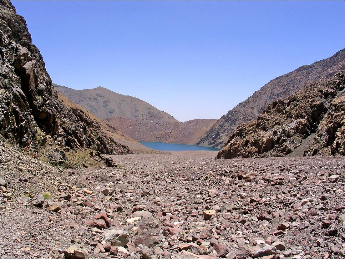 A rocky area with a lake in the background

Description automatically generated