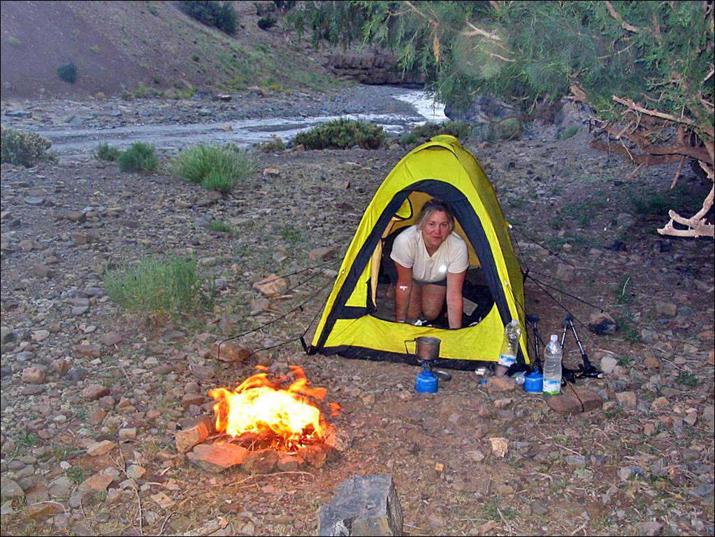 A person in a tent by a fire

Description automatically generated