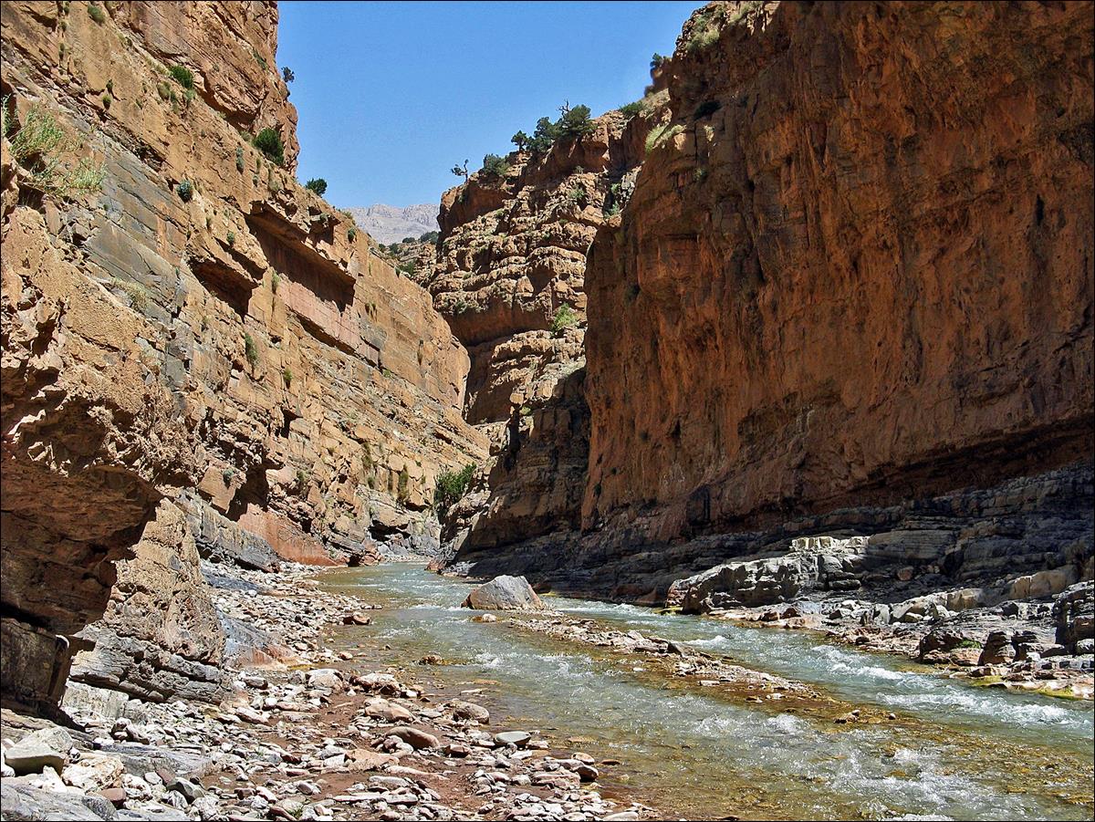 A river running through a canyon with Samari Gorge in the background

Description automatically generated