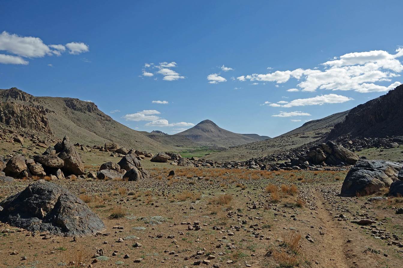 A rocky landscape with a mountain in the background

Description automatically generated
