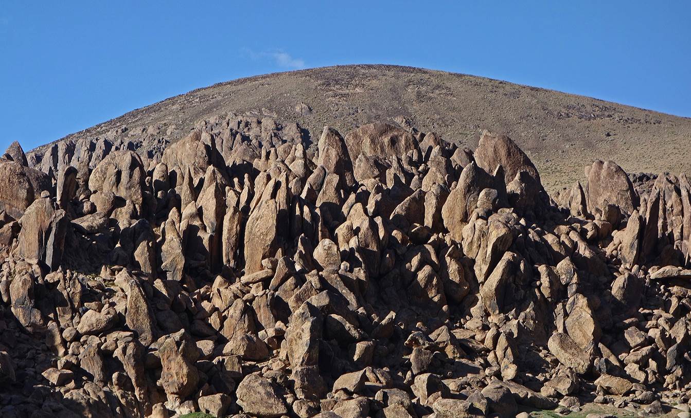 A large rocky mountain with a blue sky

Description automatically generated