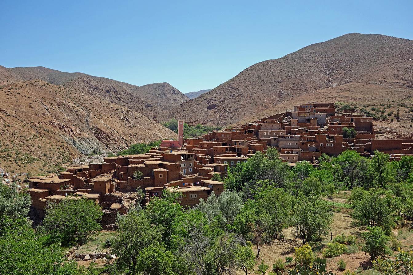A village in the mountains with Atlas Mountains in the background

Description automatically generated