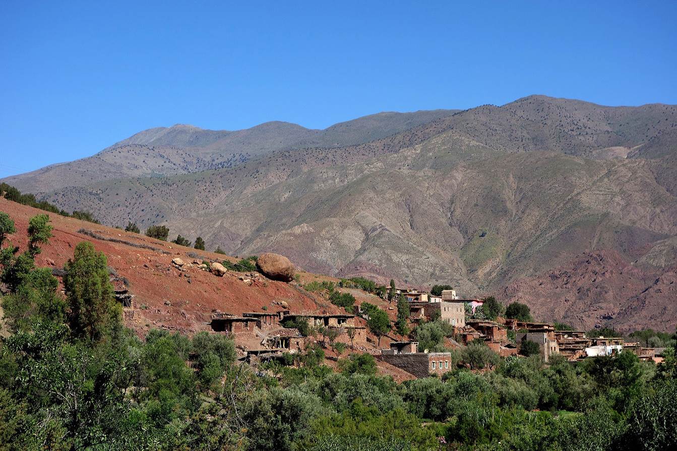 A village in the mountains with Atlas Mountains in the background

Description automatically generated