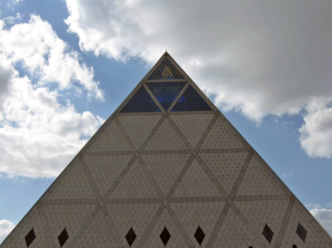 A triangular building with blue sky and clouds

Description automatically generated