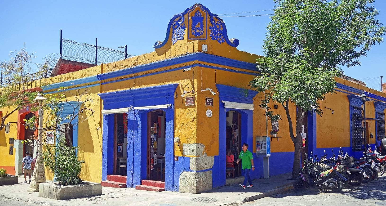 A yellow and blue building with a person walking in front of it

Description automatically generated